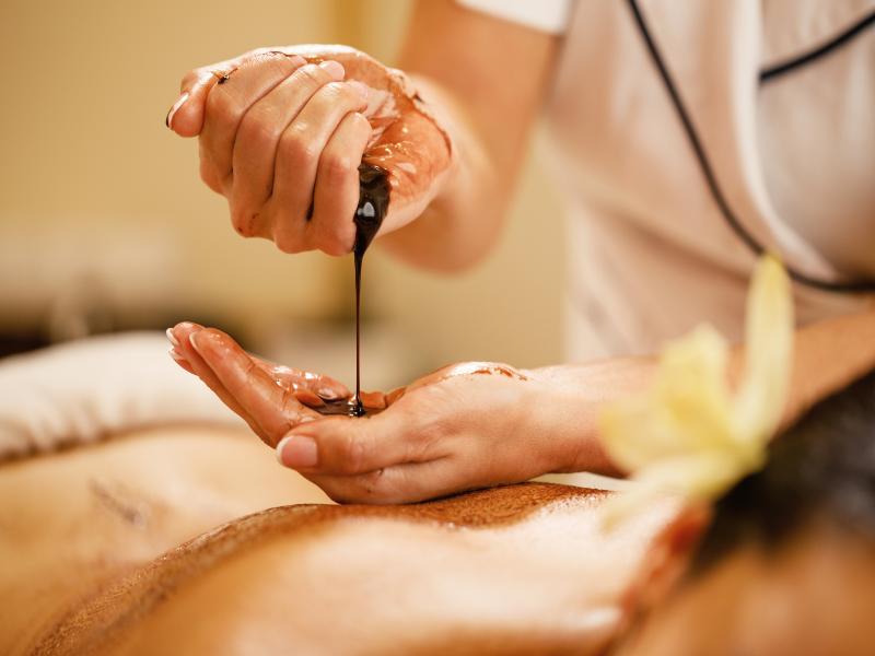 closeup-massage-therapist-pouring-hot-chocolate-her-hands-before-spa-treatment